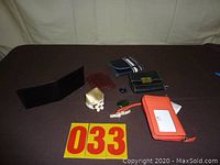 Overview photo showing all five wallets arranged on a dark surface including black, red, and orange wallets plus a gold coin purse.