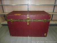 Front view of the large maroon trunk with brass hardware and locks.