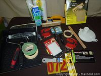 Photo showing full lot of painting supplies including paint trays, rollers, brushes, masking tape, paint pour lid and other painting accessories