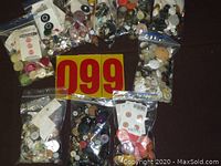 Overview of 10 small plastic bags with different buttons in many colors and sizes laid out on dark surface