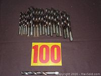 Top-down view of 20 metal twist drill bits arranged side by side showing different sizes.