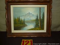 Full view of framed mountain landscape painting with trees and water reflecting the mountain.