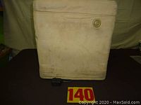 Front side of the ottoman showing beige fabric with control dial and power adapter on the floor.