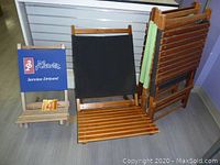 View of beach chairs folded flat showing two black fabric seats and one wooden child's chair