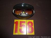 Calvin Klein prescription sunglasses placed in a black hard case, photos show front and side views confirming branding and frame style.