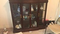 Front view of redwood display cabinet with glass doors and displayed figurines inside.