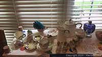 Photo showing the full set of teapot, milk jug, assorted bone china cups and saucers, decorative small china shoes, and glassware.