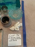 Photo showing several items on carpet including two silver candle holders, small blue glass plate with raised bubbles, white coral sculpture, and white ceramic vase with Kaiser marking.