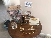 Photo showing overall lot on a round wooden table: the amethyst quartz lamp, two hummingbird paperweights, a black metal plate holder, and white bone china box with gold leaf handle.