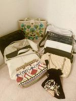 Photo showing the full assortment of purses and clutches arranged on carpeted floor corner, showing variety in styles and materials.