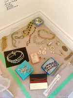 Overview of the costume jewelry lot arranged on carpet including necklaces, bracelets, pendants, and earrings.