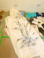 Ivory Japanese silk hostess gown with blue-grey bamboo pattern laid out on floor, surrounded by women's blouses and gloves.