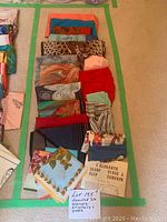 Photo showing multiple silk scarves in different colors and patterns laid out on carpet including reds, blues, animal prints, florals and abstract designs.