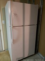 Front view of white Maytag Plus refrigerator and freezer unit with top freezer door and bottom refrigerator door.