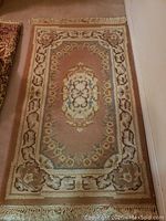 Photo of a beige and pastel color area rug with geometric and floral pattern, fringes on short sides, measuring approximately 37 by 67 inches.