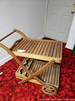 Full view of wooden bar cart showing slatted shelves and handle