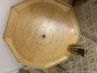 Top view of wooden crokinole table showing circular target scoring zones and small box containing wooden discs.