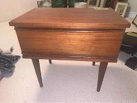 Front view of vintage cherrywood end table showing closed drawer and tapered legs.