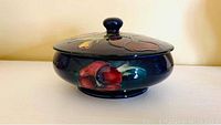 Side view of covered candy dish showing shape and painted floral design
