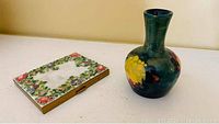 Shows both Moorcroft vase and Mother of Pearl cigarette case together on a surface.