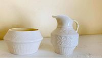 Creamer pitcher and sugar bowl showing embossed patterns and shapes.