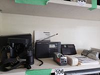 Olympus camera and accessories with radios and battery chargers on shelf