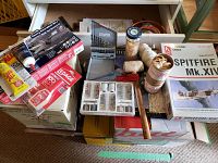 Photo showing assorted adhesives, hand drill, metal drill bits, rubber bands, string spools, and model kit boxes.