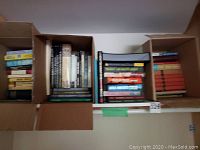 Photo of multiple boxes filled with assorted books of various sizes and colors.