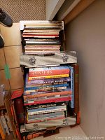 Top view photo of box filled with assorted model and war books, mostly aviation focused.
