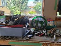 View of assorted hand tools, cords, and stained glass decor on workbench.