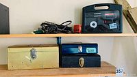 Shelf showing three metal toolboxes in yellow, blue (with label 'torch'), and black colors.