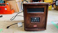 Full view of brown woodgrain Truman infrared heater with power cord and vent grille.