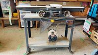 Full side view of Rockwell jointer on gray metal stand with caster wheels, showing table and motor underneath.