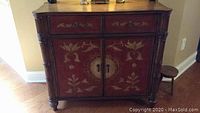 Front view of wooden cabinet showing two small drawers and two cabinet doors with floral painted detail.