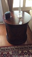 Front view of the round wooden side table with decorative wood grain and cabinet door closed.