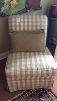 Front view of the accent chair showing checkered beige and white fabric with two beige pillows.