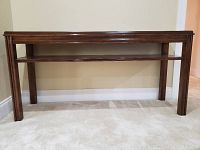 Front view of the wooden sofa table showing its leather top insert and sturdy legs.