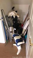 Photo showing a clustered arrangement of walkers, canes, metal padded seat chairs, and other health aids in a small room corner.