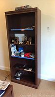 Full front view of the wooden bookcase with some contents on shelves showing condition and size