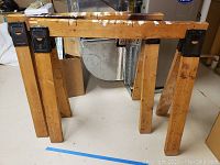 Wooden saw horse side view showing legs and top with paint marks.