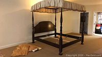 Full view of the four poster bed frame with canopy and fabric draped on the canopy top, shown assembled in a room.