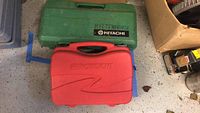 Two closed carrying cases, one green Hitachi and one red RotoZip.