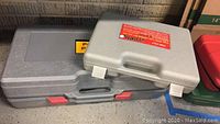 Two hard plastic cases on floor, one labeled 4 Ton Portable Puller Kit by Central Hydraulics, other smaller gray case prospected to contain body and fender set.