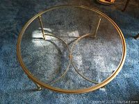 Top view of the round glass top coffee table showing the gold-tone metal frame and connecting circular braces.