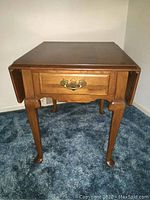 Front view of Ethan Allen drop leaf side table showing closed leaves and drawer with brass handle