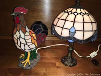 Photo showing both the rooster slag glass lamp and the Tiffany style slag glass lamp side by side on wooden surface.
