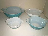 Overview of four Pyrex Cinderella mixing bowls in teal and white with Amish Butterprint pattern, different sizes.