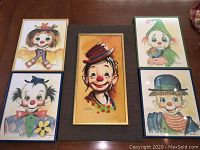 Overview of original painting and four clown prints arranged on a table