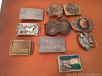 Top view of ten assorted western themed belt buckles displaying a variety of western and brand motifs.