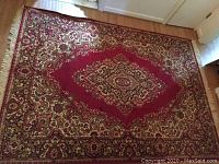 Full view of the rectangular oriental style rug on a hardwood floor showing the large central medallion and floral border patterns.